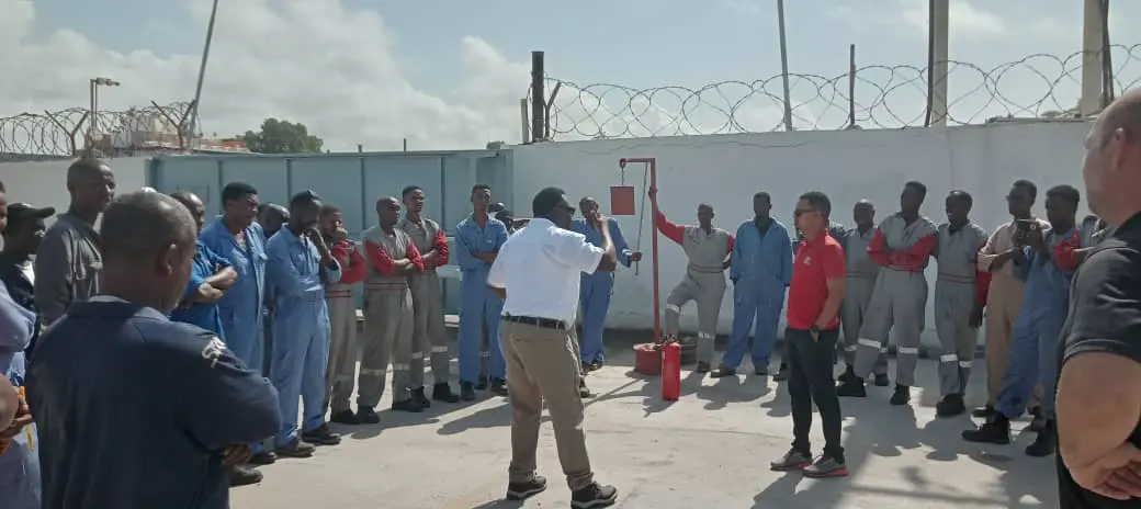 Automotive workshop employees participating in an outdoor emergency response drill in Mogadishu